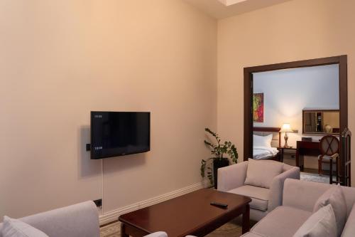 a living room with a couch and a tv on the wall at Ambassador Hotel in Bishkek
