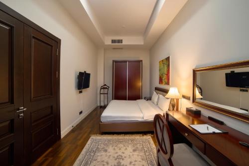 a bedroom with a bed and a desk and a mirror at Ambassador Hotel in Bishkek