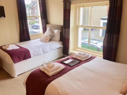 two beds in a room with a window at Salisbury Guest House in Keswick