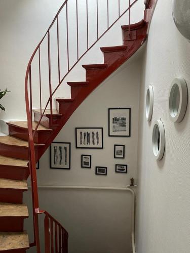 a stairway with a red railing and some framed pictures at le relais in Fontenay-Trésigny