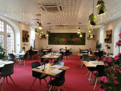 un restaurante con mesas, sillas y flores en Hôtel Restaurant Le Lion d'Or, en Gémozac