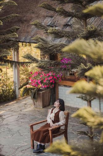 a woman sitting on a bench in a garden at The Nordic Village - Evergreen Retreat in Mộc Châu