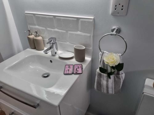 a white sink in a bathroom with a flower at Serene getaway Apartments in Maidstone