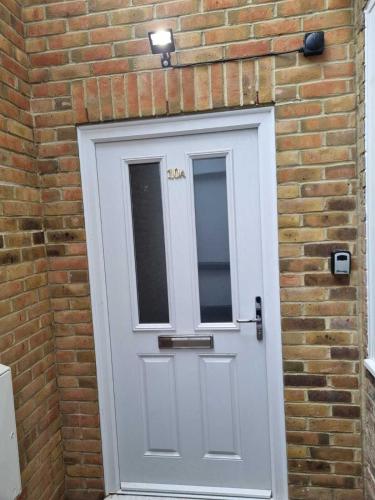 a brick wall with a white door with a window at Serene getaway Apartments in Maidstone
