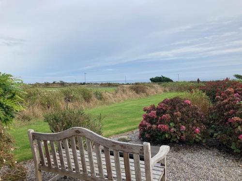 a wooden bench sitting next to some bushes and flowers at Beautiful one bed with stunning sea view in Waterford