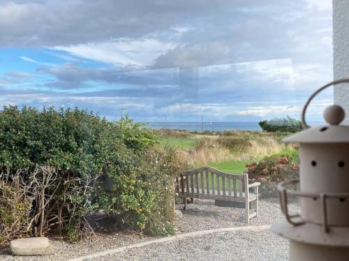 a bench sitting on a path near the ocean at Beautiful one bed apartment with stunning sea view in Waterford