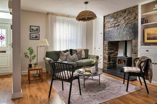 a living room with a green couch and a fireplace at Finest Retreats - Bwthyn Llechi, Slate Cottage in Blaenau-Ffestiniog