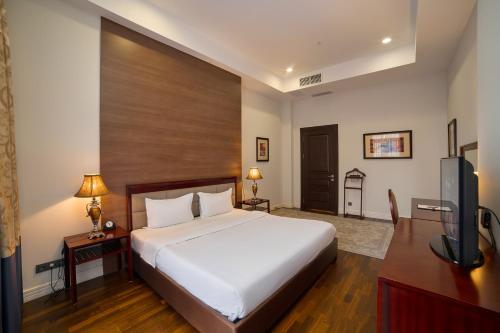a bedroom with a bed and a flat screen tv at Ambassador Hotel in Bishkek