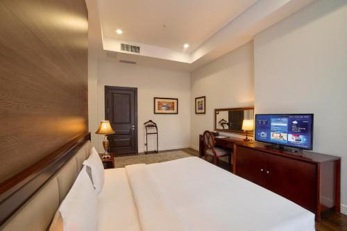 a hotel room with a bed and a desk with a television at Ambassador Hotel in Bishkek