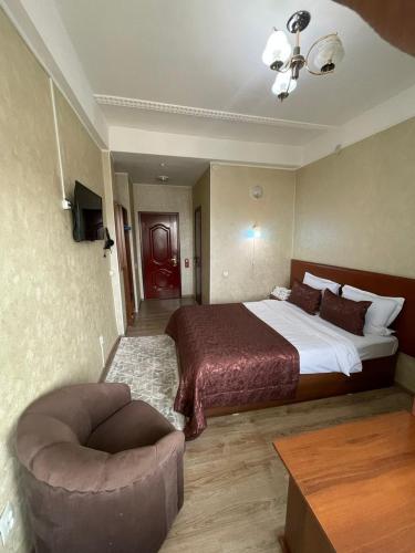 a hotel room with a bed and a chair at Hotel Osh-Nuru in Osh