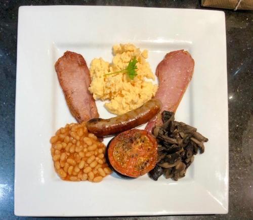 a plate of food with sausage eggs beans and mushrooms at Salisbury Guest House in Keswick