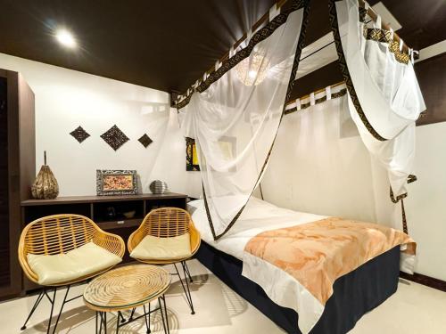 a bedroom with a canopy bed and two stools at Hotel BaliBali 伊勢佐木 in Yokohama