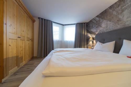 a bedroom with a large white bed with a brick wall at Eden Apartments in Siusi