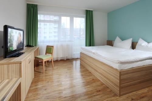 Habitación de hotel con cama y TV en Penzion Morava, en Otrokovice
