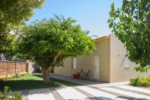 a small house with a tree in the yard at Behind The Waves in Kalamaki Heraklion