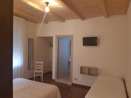 1 dormitorio con 2 camas, TV y silla en Le Corti del Casale, en Alberobello