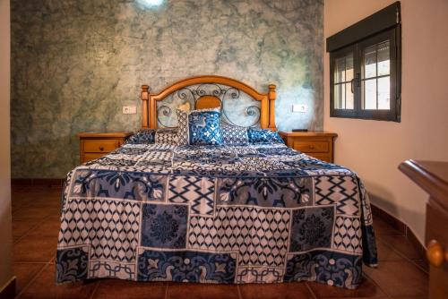 1 dormitorio con 1 cama con colcha azul y blanca en Hospedaje Rural Casa Parri, en Poveda de la Sierra