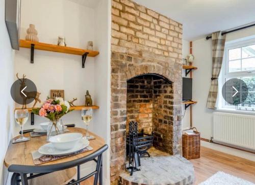 a living room with a brick fireplace and a table at Bernards Hill in Bridgnorth