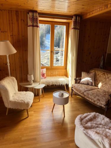 a living room with a couch and a chair and a window at Heida, studio ensoleillé au village avec magnifique vue sur la Dent-Blanche in Evolène