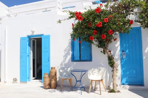 a house with blue doors and a tree with red flowers at Hotel Madalena in Mikonos