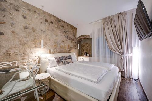 una camera da letto con un grande letto bianco e un muro di Arcadia Rooms a Merano