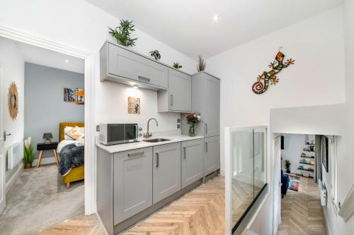 a kitchen with white cabinets and a living room at Finest Retreats - The Bank House in Boroughbridge