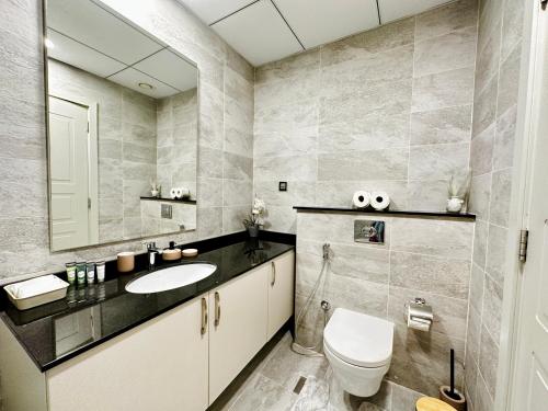a bathroom with a sink and a toilet and a mirror at PR25 - Cozy 1BR in Polo Residences in Dubai