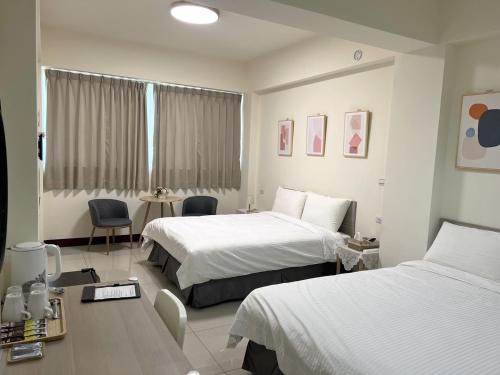 een hotelkamer met 2 bedden en een tafel en stoelen bij Hourlight Homestay in Ch'iung-lin