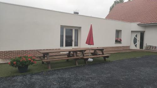 a picnic table with an umbrella on the side of a building at Camping la Haie Penée **** in Saint-Quentin-en-Tourmont