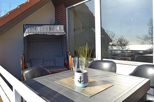 a table with chairs and a vase on a balcony at Quartier Meerblick in Fehmarn