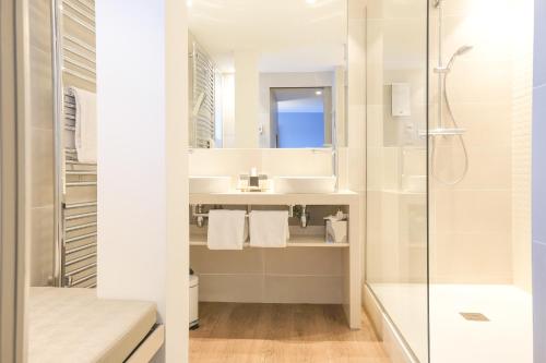 La salle de bains blanche est pourvue d'une douche et d'un lavabo. dans l'établissement Thalazur Carnac - Hôtel & Spa, à Carnac