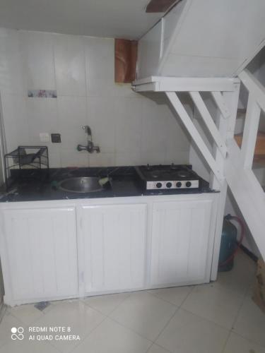 una cocina con armarios blancos, un lavabo y una escalera en Rdc Residence Alakhawayn pour famille, en Ifrane