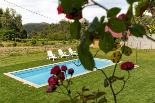 a swimming pool in a yard with two lawn chairs at Casa do Castelo em Arnóia in Celorico de Basto