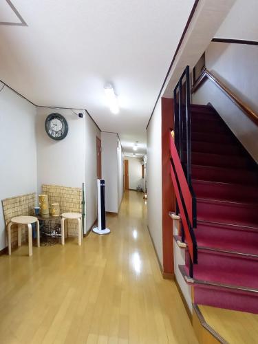 a hallway with stairs and a clock on the wall at HOTEL HOUSE LEE in Tokyo