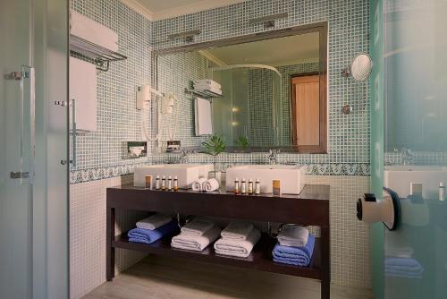 a bathroom with two sinks and a mirror and towels at Aldemar Olympian Village in Olympia