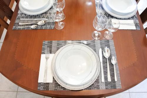 un tavolo in legno con piatti bianchi e argenteria di Barbara's sweet home Preveza a Preveza