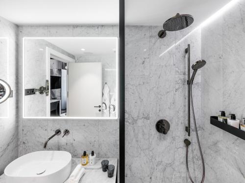 a white bathroom with a shower and a sink at The Amauris Vienna - Relais & Châteaux in Vienna
