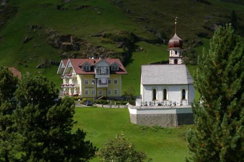 a large house and a church on a green hill at Appartement Wildspitz' in Vent