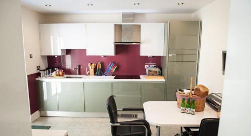 a kitchen with white cabinets and a table with chairs at Acorns with own hot tub, romantic escape, close to Lyme Regis in Uplyme