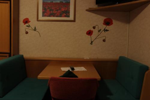a table and two chairs with red flowers on the wall at Hotel Villa Emilia in Ortisei