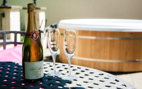 a bottle of wine and two wine glasses on a table at Acorns with own hot tub, romantic escape, close to Lyme Regis in Uplyme