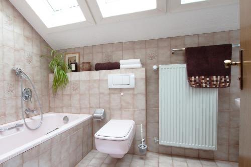 a bathroom with a tub and a toilet and a shower at Ferienhaus Antdorfer Gartenglück in Antdorf