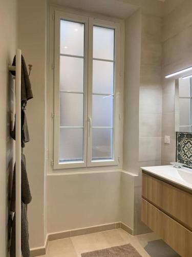 La salle de bains blanche est pourvue d'une fenêtre et d'un lavabo. dans l'établissement Cosy Joliette, central, climatisé, 2 chambres, WIFI, Garage, à Marseille