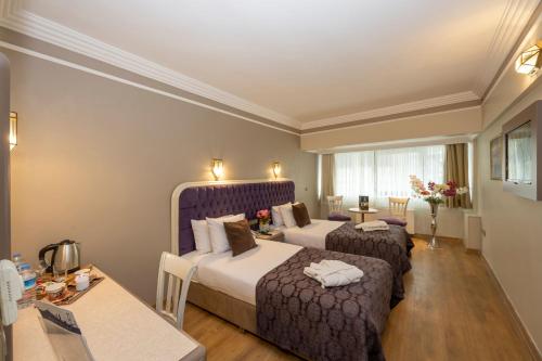 a hotel room with two beds and a table at Grand Anka Hotel in Istanbul