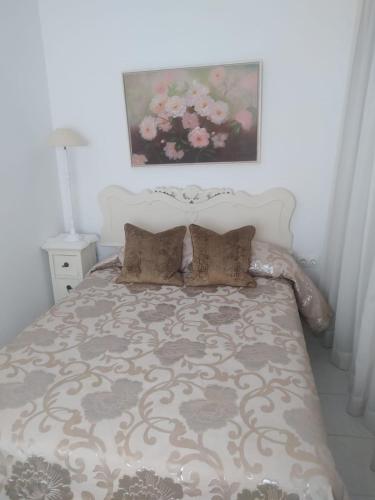 a bed with two pillows and a painting on the wall at Ático muy Luminoso en el Casco Antiguo in Córdoba