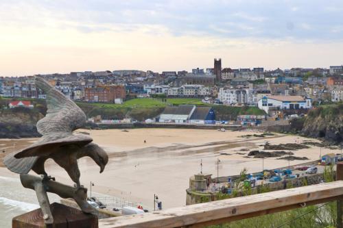 a statue of a bird perched on a fence overlooking a beach at Seaside Apartment in Newquay