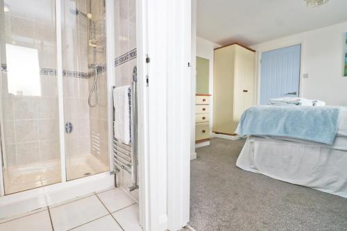 a bathroom with a shower and a bed in a room at Seaside Apartment in Newquay