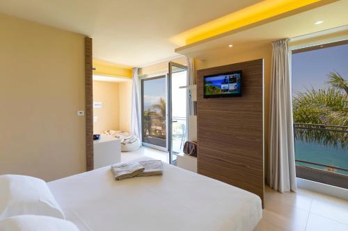 a bedroom with a white bed and a large window at Blue Bay Resort in Capo Vaticano