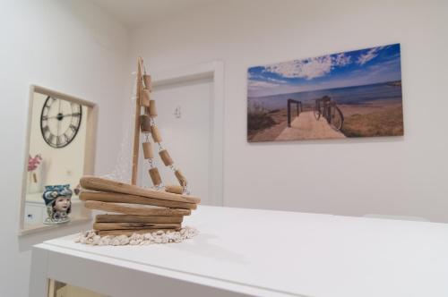 a white table with a clock and a pile of wood at RAUDINO ROOMS in Siracusa