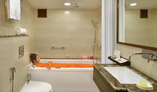 a woman sitting in a bath tub in a bathroom at RK Sarovar Portico in Srinagar